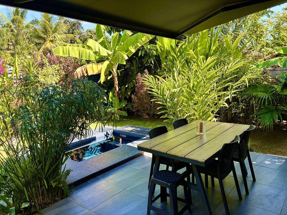 Terrasse couverte avec table, au bord de la piscine